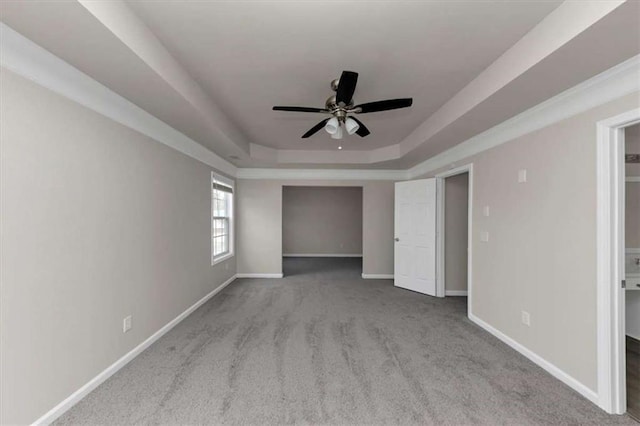 unfurnished bedroom with light carpet, ceiling fan, and a tray ceiling