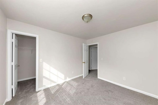 unfurnished bedroom featuring a walk in closet, carpet, and a closet