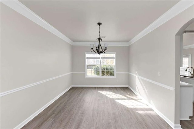 unfurnished dining area with dark hardwood / wood-style flooring, crown molding, and a chandelier