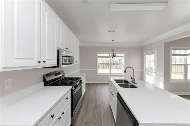 kitchen featuring sink, hanging light fixtures, an island with sink, stainless steel appliances, and white cabinets