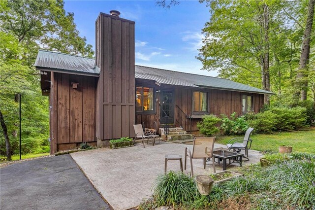 back of property with a patio and an outdoor fire pit