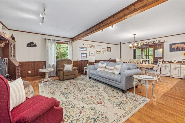 living room featuring a notable chandelier, light hardwood / wood-style floors, crown molding, track lighting, and beam ceiling