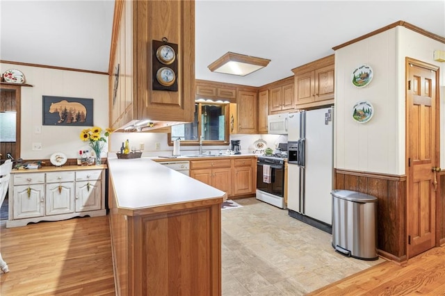 kitchen featuring sink, light hardwood / wood-style flooring, ornamental molding, kitchen peninsula, and white appliances