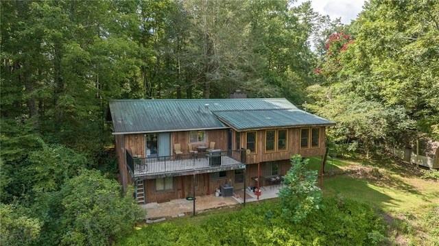 rear view of house featuring a wooden deck, a yard, and a patio