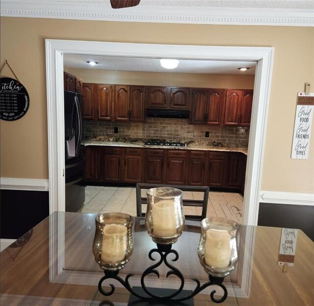 6210 Douglas Manor Ct, Douglasville, GA 30134 - kitchen with gas stovetop, under cabinet range hood, backsplash, black fridge, and light countertops