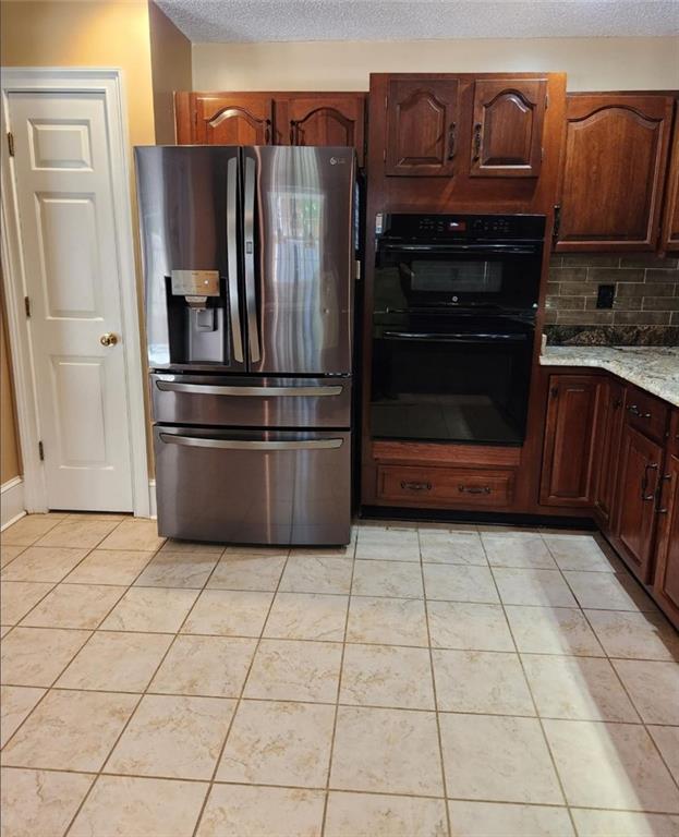 6210 Douglas Manor Ct, Douglasville, GA 30134 - kitchen with stainless steel fridge with ice dispenser, a textured ceiling, backsplash, light tile patterned floors, and light stone counters