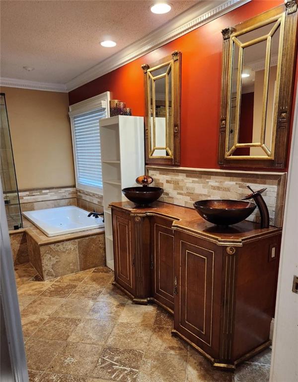6210 Douglas Manor Ct, Douglasville, GA 30134 - bathroom featuring a garden tub, double vanity, crown molding, a textured ceiling, and tasteful backsplash