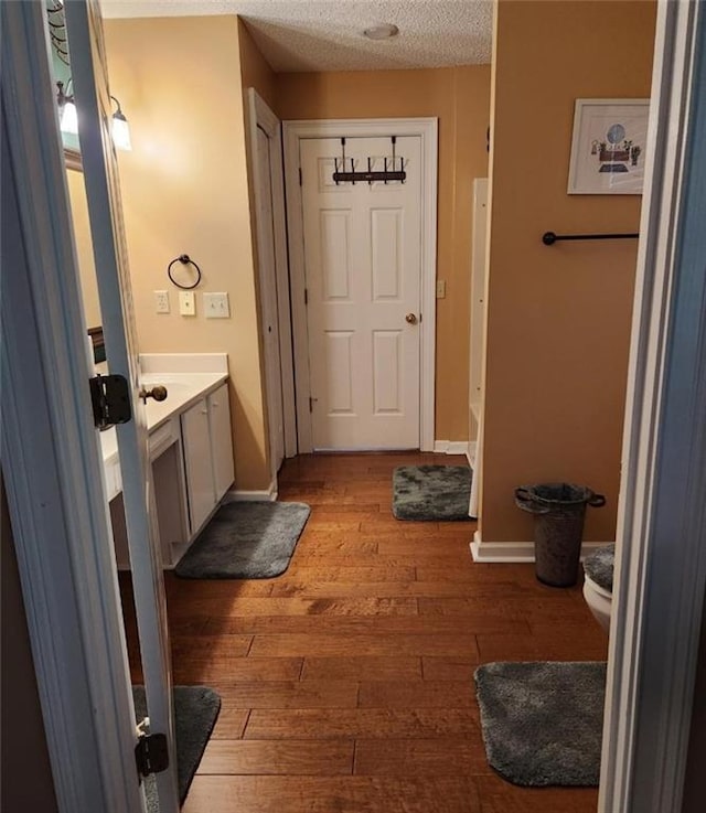 6210 Douglas Manor Ct, Douglasville, GA 30134 - bathroom featuring vanity, wood-type flooring, a textured ceiling, toilet, and baseboards