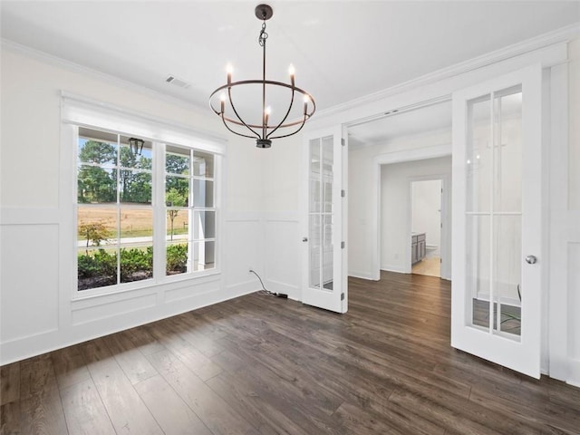 unfurnished dining area featuring french doors, dark hardwood / wood-style flooring, an inviting chandelier, and crown molding