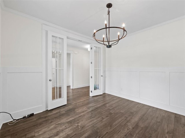 unfurnished dining area featuring dark wood-type flooring, french doors, crown molding, and a chandelier