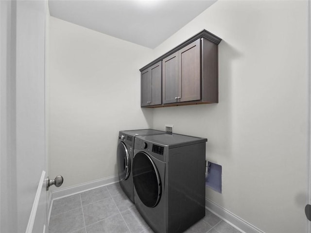 clothes washing area with washer and clothes dryer, light tile patterned floors, and cabinets