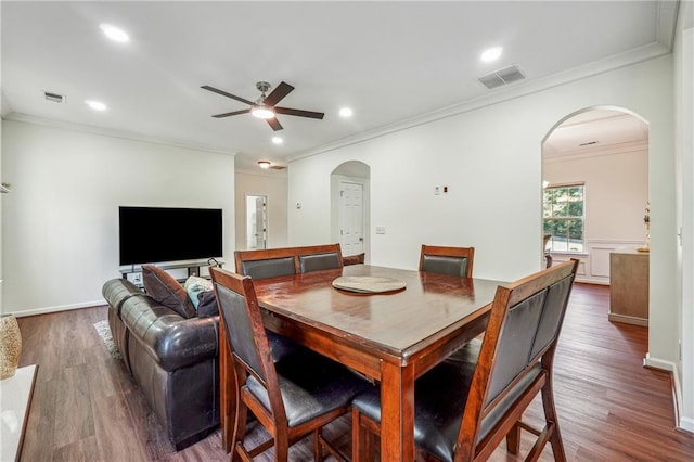 dining space featuring dark wood-style floors, arched walkways, crown molding, recessed lighting, and visible vents