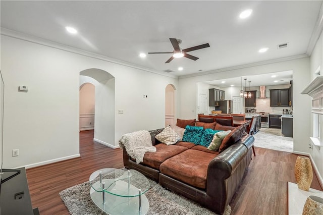 living area featuring arched walkways, baseboards, wood finished floors, and recessed lighting