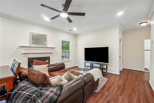 living area with baseboards, ceiling fan, ornamental molding, wood finished floors, and a fireplace