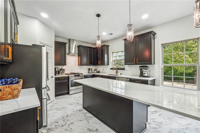 kitchen with marble finish floor, decorative backsplash, appliances with stainless steel finishes, a sink, and wall chimney range hood