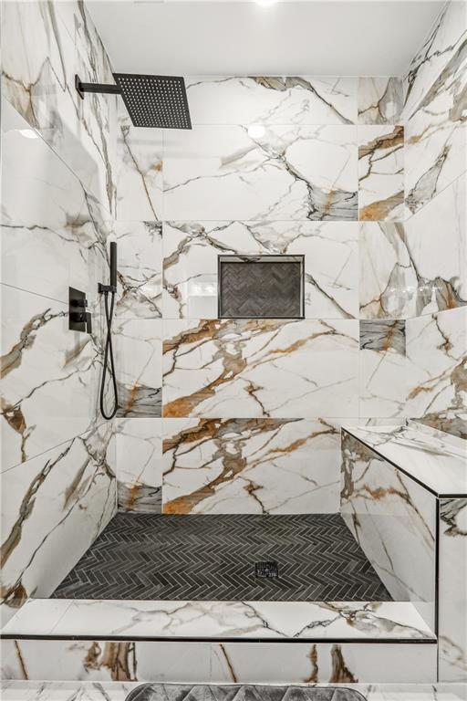 interior details featuring a marble finish shower