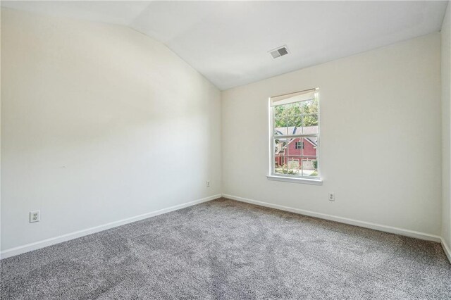 spare room featuring lofted ceiling, baseboards, visible vents, and carpet flooring