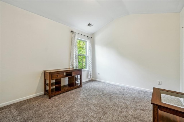 spare room with carpet floors, visible vents, vaulted ceiling, and baseboards