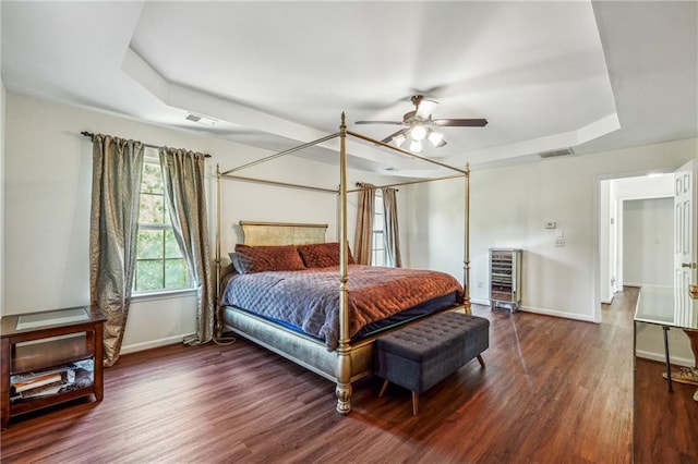 bedroom featuring wood finished floors, a raised ceiling, visible vents, and baseboards