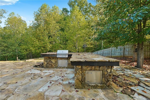 view of patio with grilling area, an outdoor kitchen, and fence