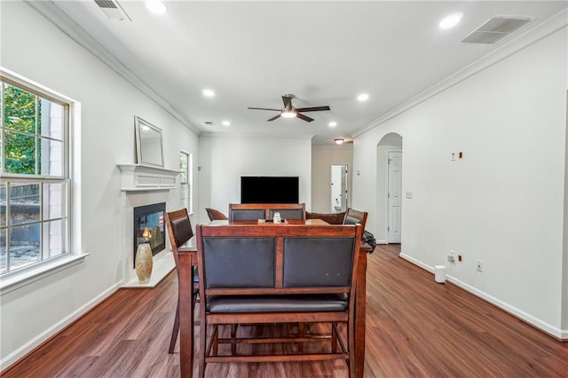 living room with arched walkways, visible vents, a glass covered fireplace, and wood finished floors