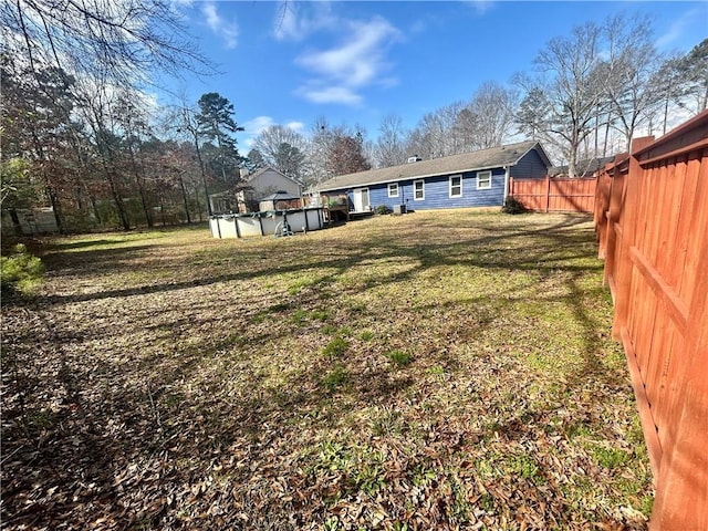 rear view of house with a covered pool and a lawn