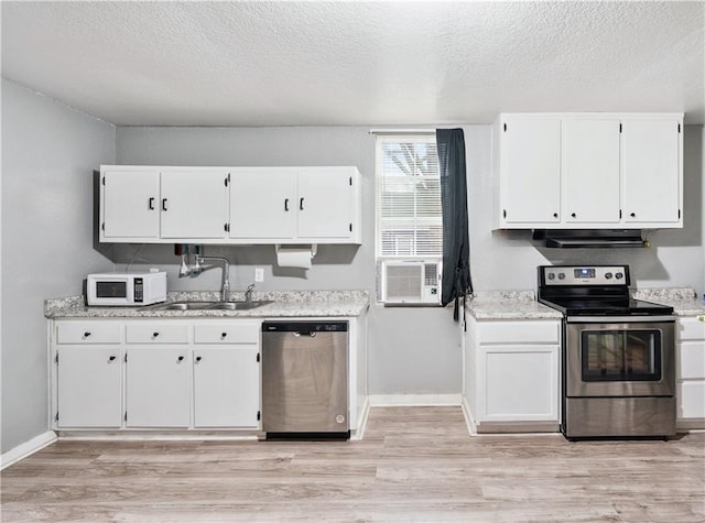 kitchen featuring stainless steel appliances, sink, white cabinets, and light wood-type flooring