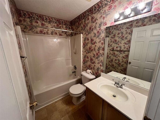 full bathroom featuring toilet, vanity, a textured ceiling, and bathtub / shower combination