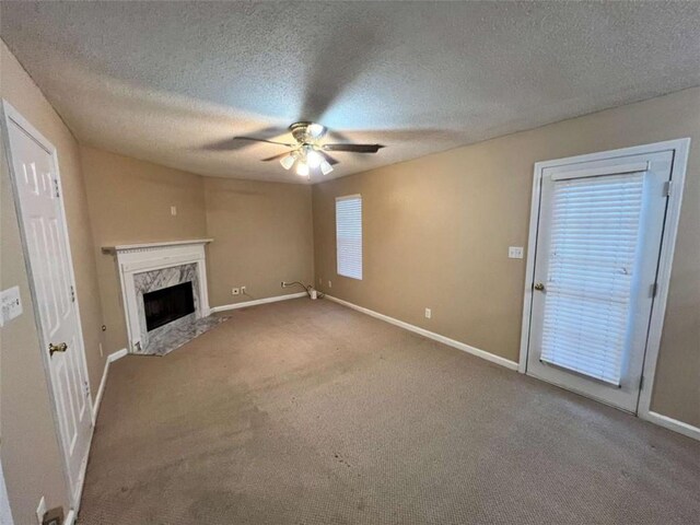 unfurnished living room featuring a fireplace, ceiling fan, carpet floors, and a textured ceiling