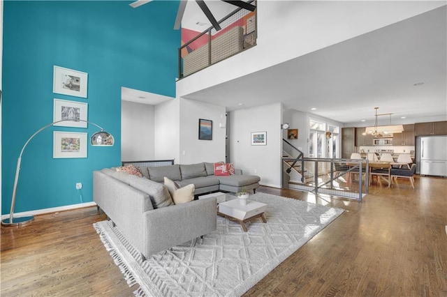 living area with baseboards, wood finished floors, an inviting chandelier, stairs, and recessed lighting