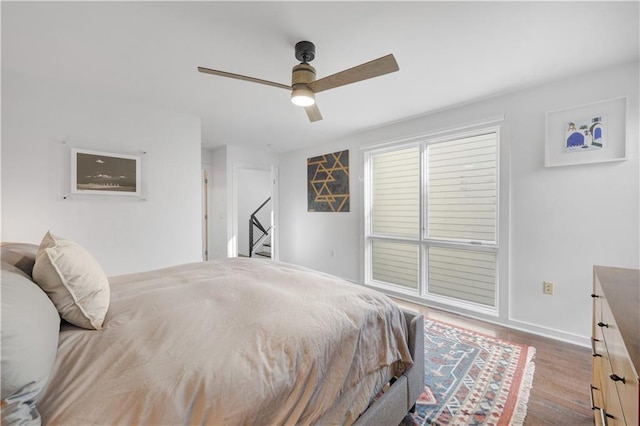 bedroom with ceiling fan, baseboards, and wood finished floors