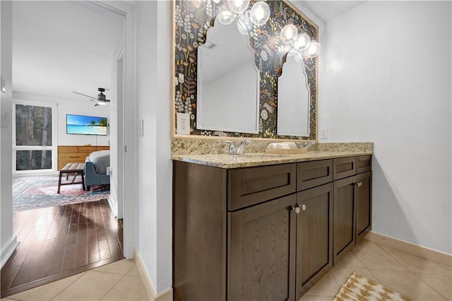 ensuite bathroom with double vanity, connected bathroom, a ceiling fan, tile patterned floors, and a sink