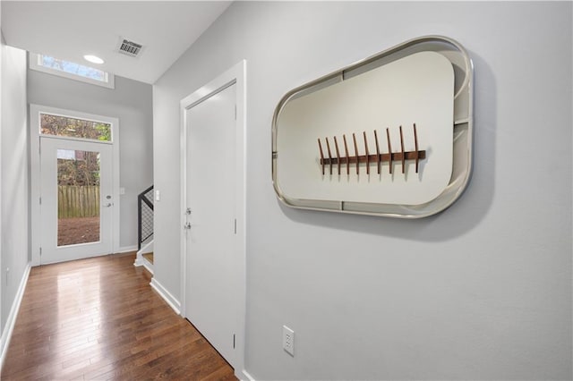 hallway with hardwood / wood-style flooring, baseboards, and visible vents