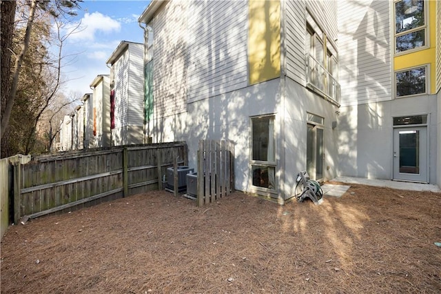 view of side of home featuring central AC unit, fence, and stucco siding