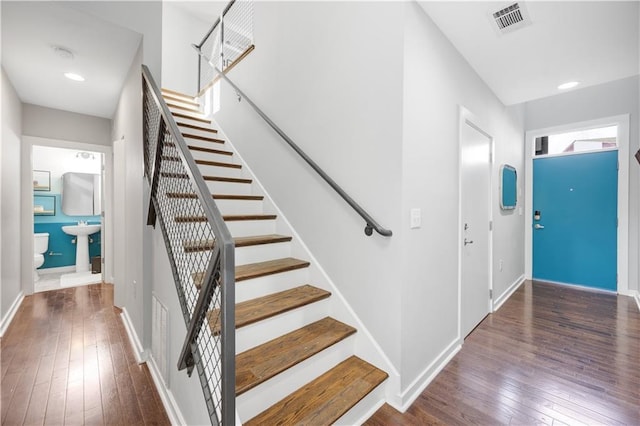 stairway featuring wood-type flooring, visible vents, baseboards, and recessed lighting