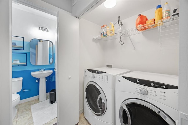 clothes washing area with laundry area, light tile patterned floors, baseboards, washing machine and dryer, and a sink