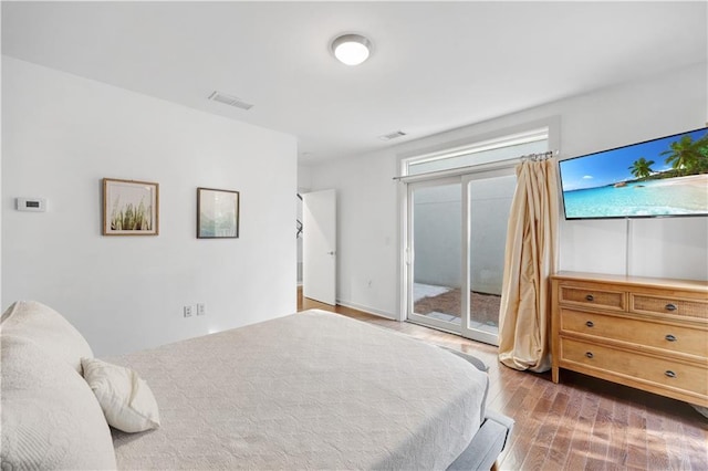 bedroom featuring access to exterior, visible vents, and wood finished floors