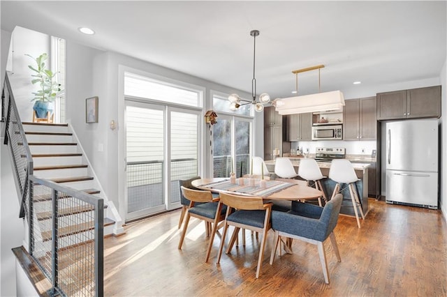 dining space with baseboards, wood finished floors, an inviting chandelier, stairs, and recessed lighting