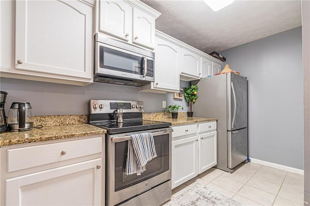 970 Sidney Marcus Blvd Unit 1217, Atlanta, GA 30324 - kitchen featuring light tile patterned flooring, a textured ceiling, appliances with stainless steel finishes, white cabinetry, and light stone counters