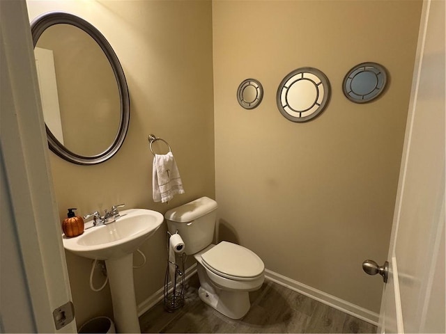 bathroom with toilet, wood-type flooring, and sink