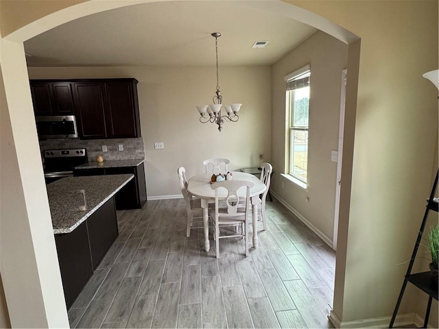 kitchen featuring backsplash, sink, appliances with stainless steel finishes, decorative light fixtures, and a chandelier