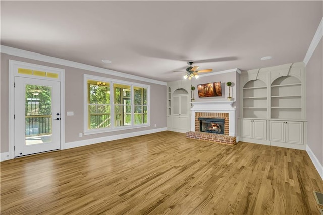 4424 Longmead Rd, Flowery Branch, GA 30542 - unfurnished living room featuring ornamental molding, light wood-type flooring, a ceiling fan, a fireplace, and built in shelves