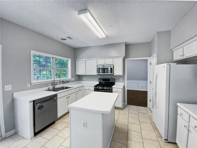 kitchen with sink, a kitchen island, a textured ceiling, white cabinets, and appliances with stainless steel finishes