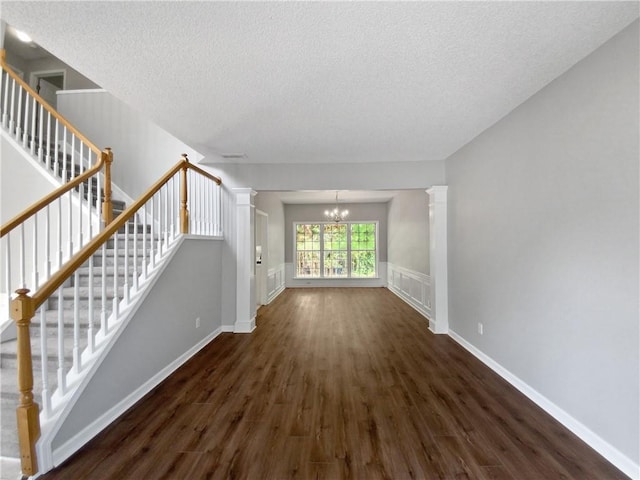 unfurnished living room with dark hardwood / wood-style flooring, a chandelier, and a textured ceiling