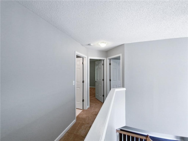 corridor with light carpet and a textured ceiling