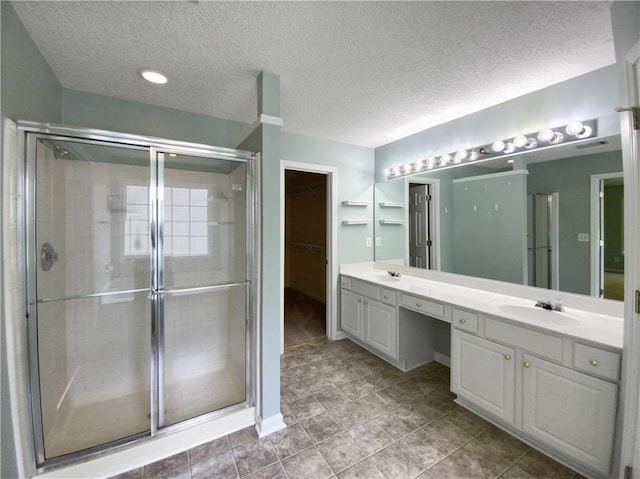 bathroom with vanity, an enclosed shower, and a textured ceiling