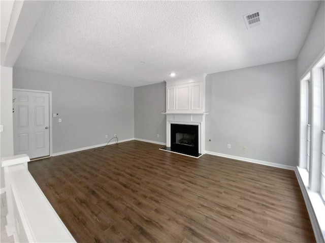 unfurnished living room featuring a fireplace, dark wood-type flooring, and a textured ceiling