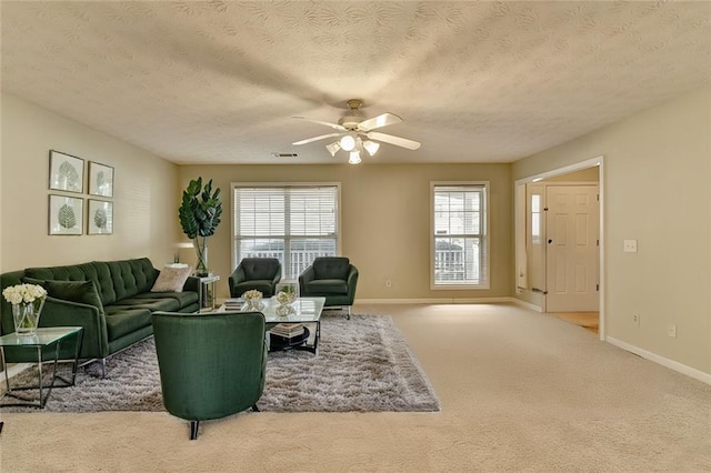 carpeted living room featuring a textured ceiling, ceiling fan, and a wealth of natural light