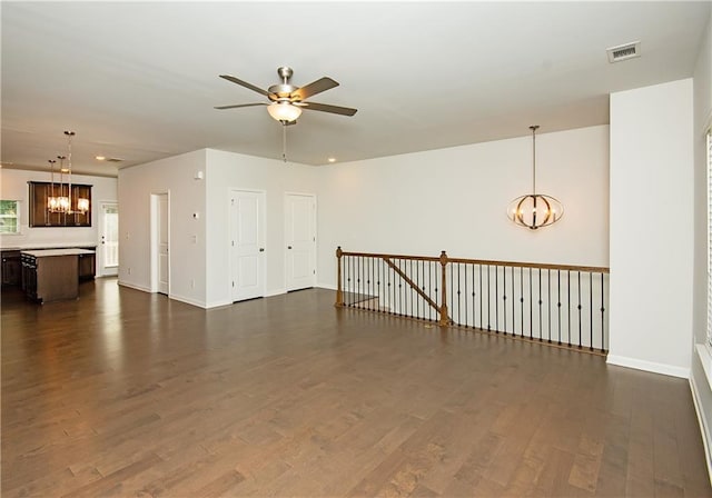 unfurnished room with ceiling fan with notable chandelier and hardwood / wood-style flooring