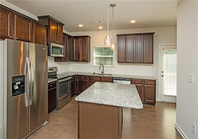 kitchen with appliances with stainless steel finishes, sink, wood-type flooring, and a kitchen island